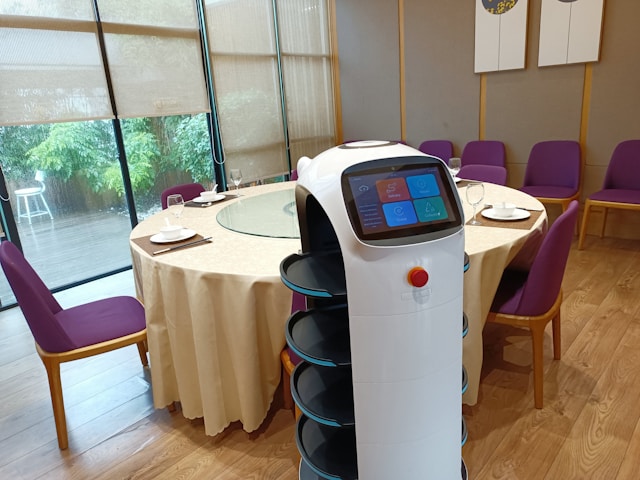 An image of a robot server inside of a restaurant next to an empty table.